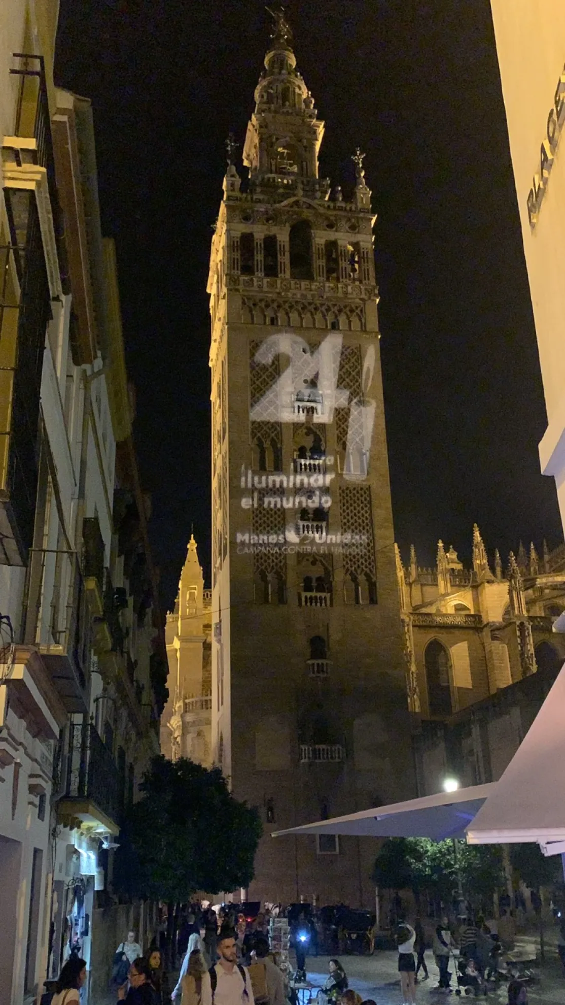 Giralda de Sevilla con el logo de Las 24 Horas de Manos Unidas