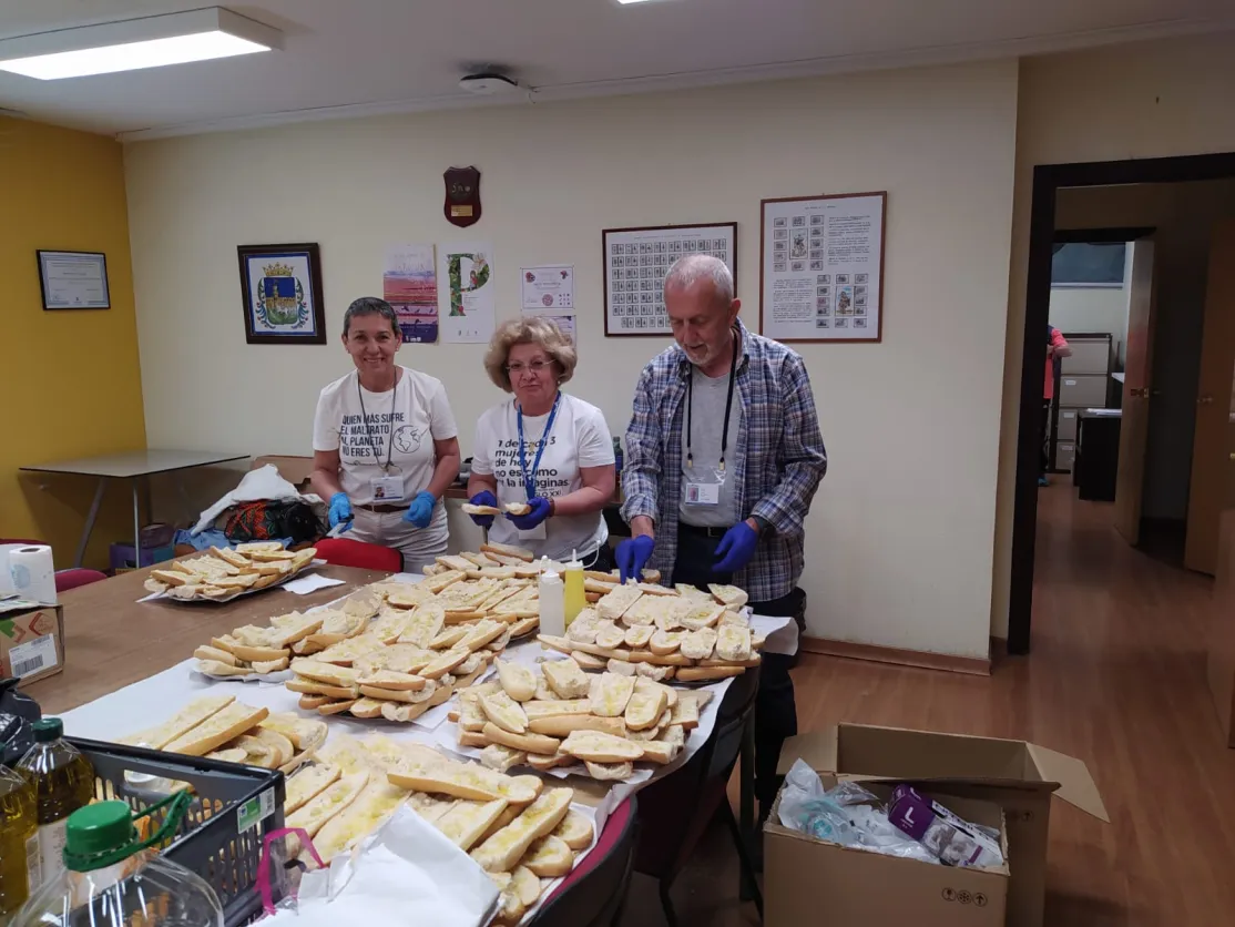 Voluntarios de Manos Unidas preparando el pan con aceite.