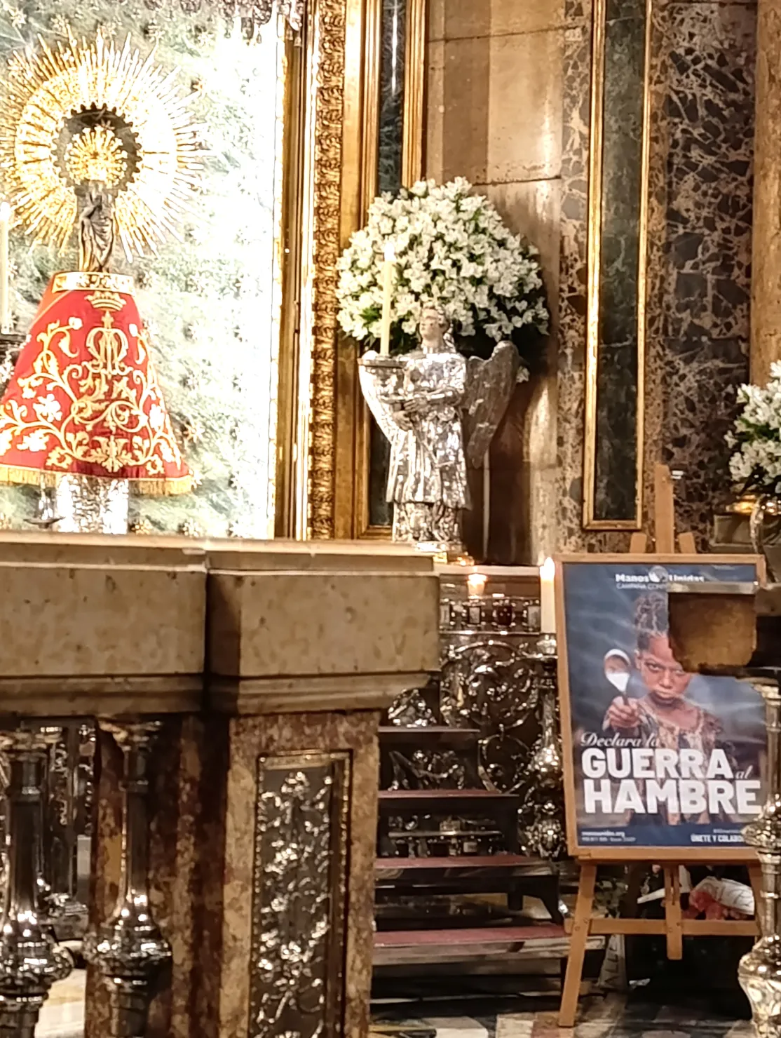 Cartel de la Campaña "Declara la guerra al hambre" a los pies de la Virgen del Pilar