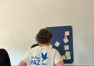 Un joven voluntario observa un mural con notas adhesivas durante una dinámica de reflexión en el aula.