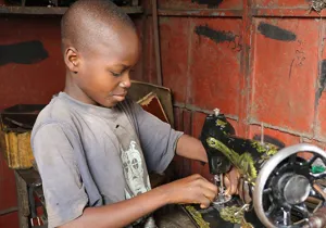 Un niño arregla una máquina de coser en el mercado Dantopka en Cotonou, Benín. Foto Iciar de la Peña-Manos Unidas