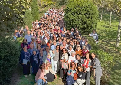 Numeroso grupo de participantes en las Jornadas de Formación 2026 de Manos Unidas posa al aire libre, entre setos y árboles, en El Escorial.