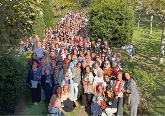 Numeroso grupo de participantes en las Jornadas de Formación 2026 de Manos Unidas posa al aire libre, entre setos y árboles, en El Escorial.