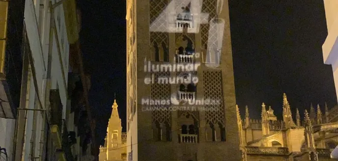 Giralda de Sevilla con el logo de Las 24 Horas de Manos Unidas