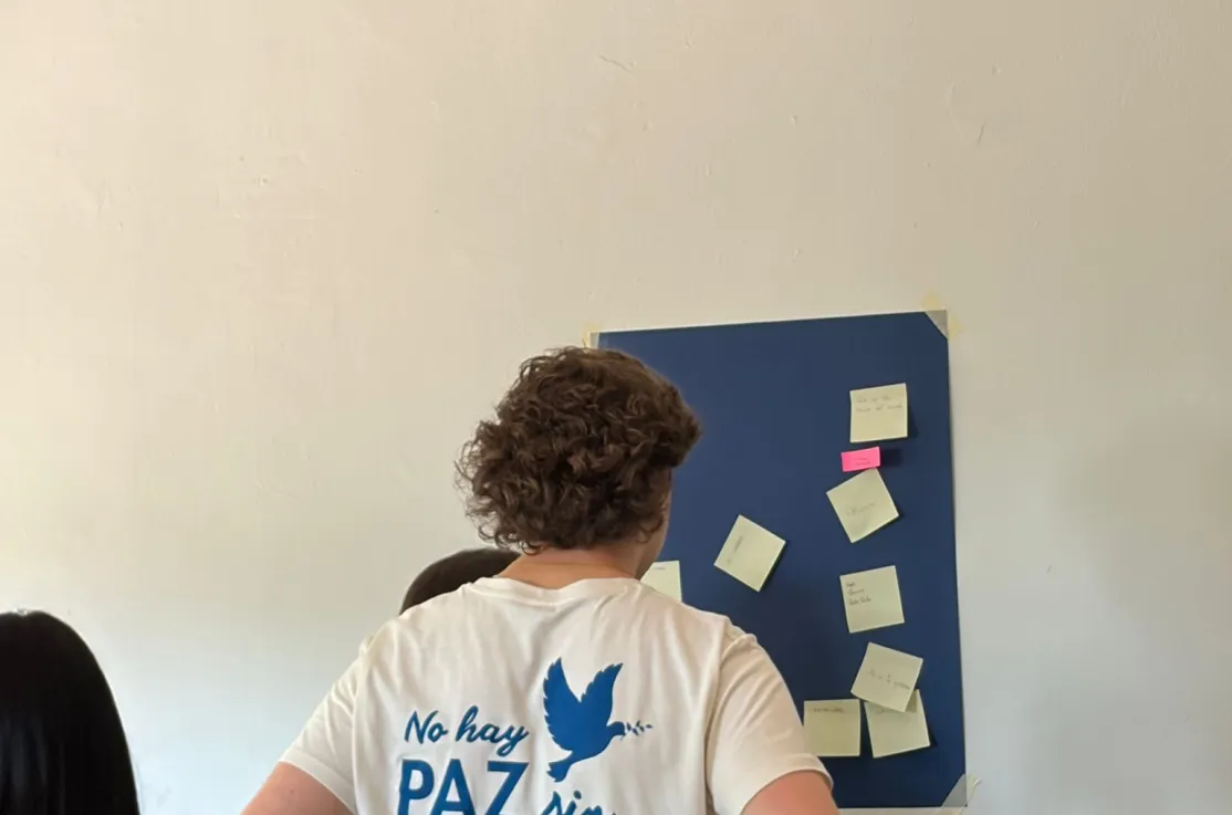 Un joven voluntario observa un mural con notas adhesivas durante una dinámica de reflexión en el aula.