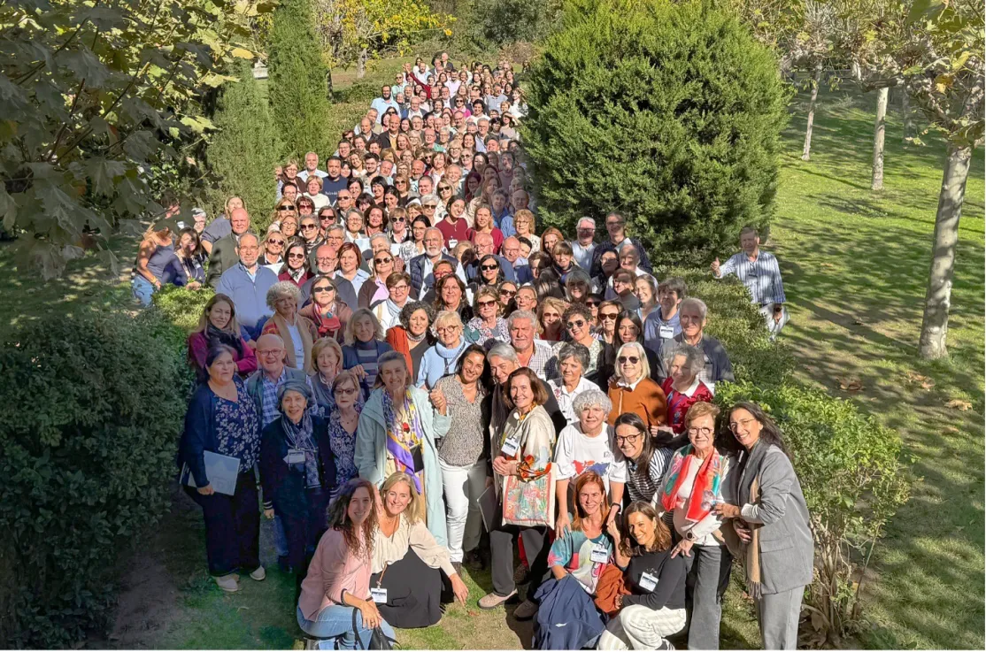 Numeroso grupo de participantes en las Jornadas de Formación 2026 de Manos Unidas posa al aire libre, entre setos y árboles, en El Escorial.