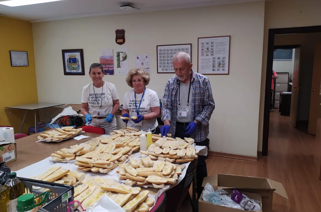 Voluntarios de Manos Unidas preparando el pan con aceite.
