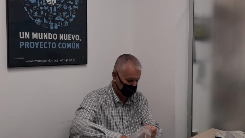 Uno de los voluntarios de Manos Unidas Valencia clasificando monedas y billetes.
