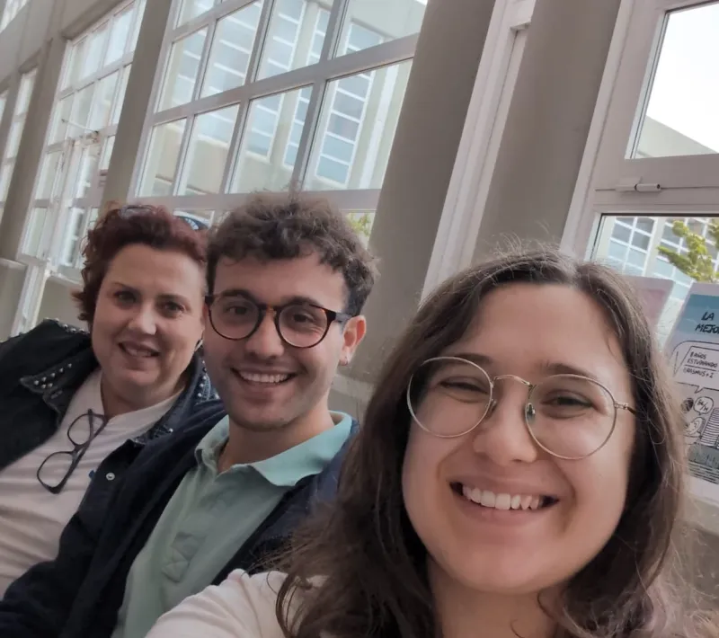 Tres integrantes de Manos Unidas sonríen durante su participación en la Feria de Itinerarios Profesionales de la Facultad de Derecho de Cáceres.