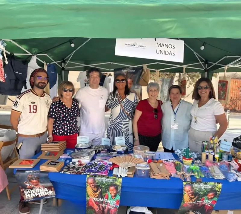 Voluntarios de MANOS UNIDAS reciben la visita de Pepe Rodríguez en su puesto de venta.