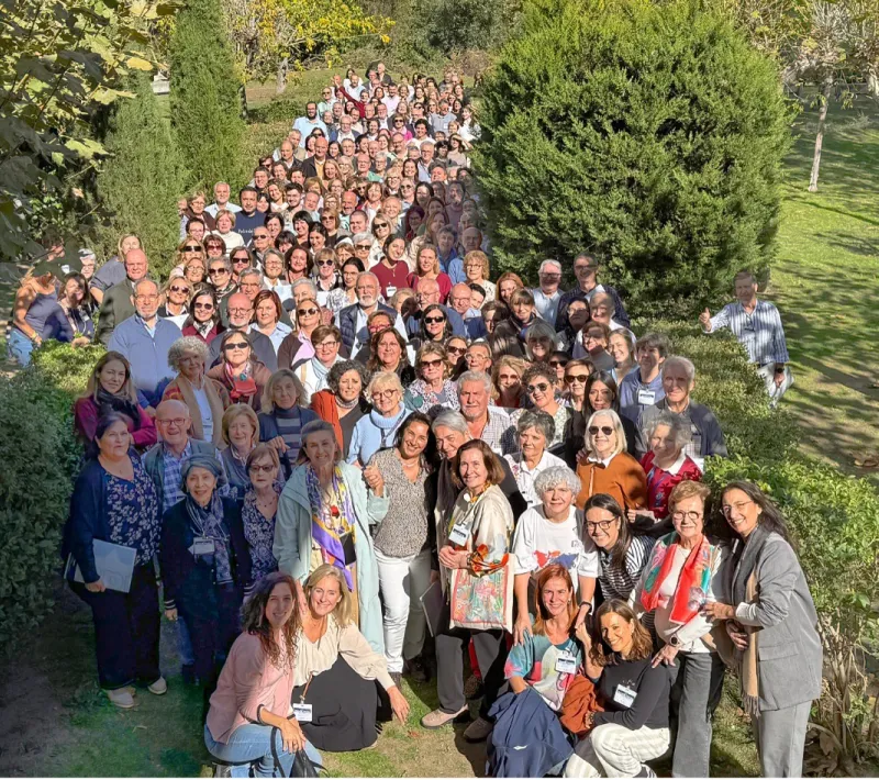 Numeroso grupo de participantes en las Jornadas de Formación 2026 de Manos Unidas posa al aire libre, entre setos y árboles, en El Escorial.