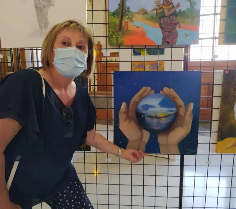 Pintora de la Escuela Gaia junto a su obra en la exposición de la Estación del Norte.
