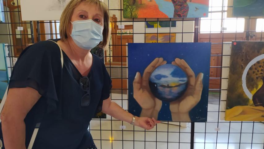 Pintora de la Escuela Gaia junto a su obra en la exposición de la Estación del Norte.