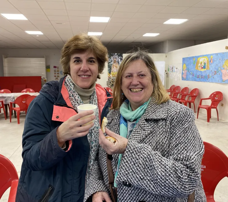 Patricia y Pilar con un trozo de pan y un vaso de caldo.