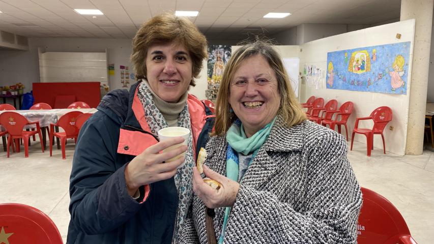 Patricia y Pilar con un trozo de pan y un vaso de caldo.