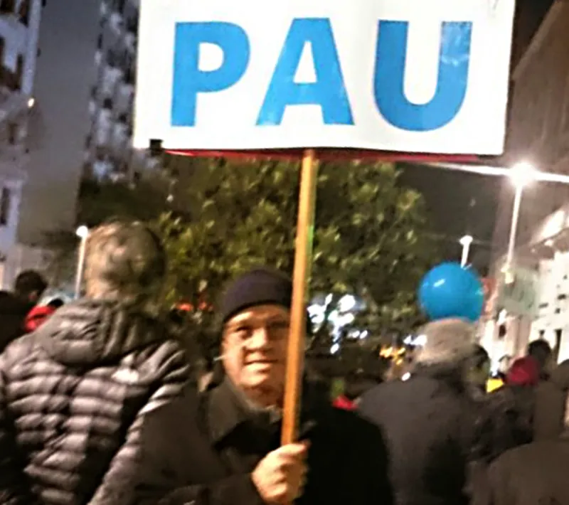 Fernando Sanz, de Manos Unidas Barcelona, enseña con orgullo un cartel con la palabra PAZ.