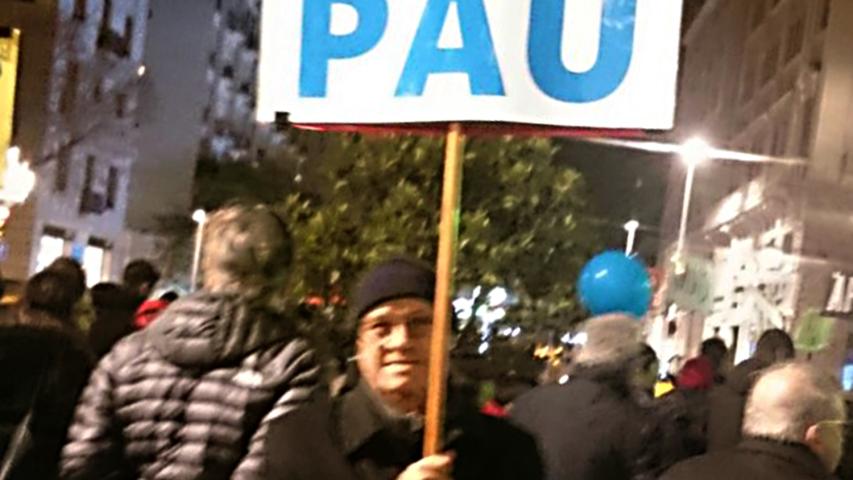 Fernando Sanz, de Manos Unidas Barcelona, enseña con orgullo un cartel con la palabra PAZ.