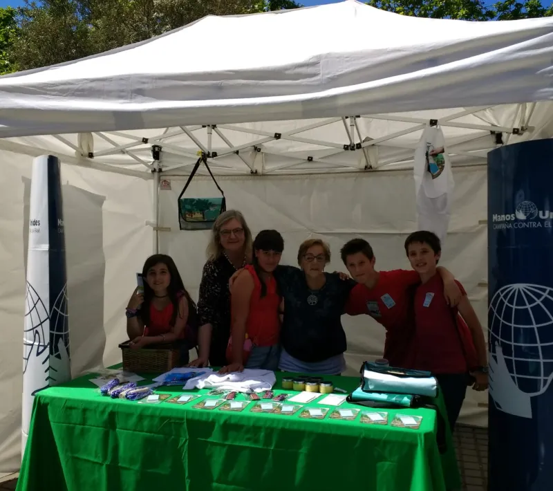 Stand de Manos Unidas con alumnos, en el mercado cooperativo