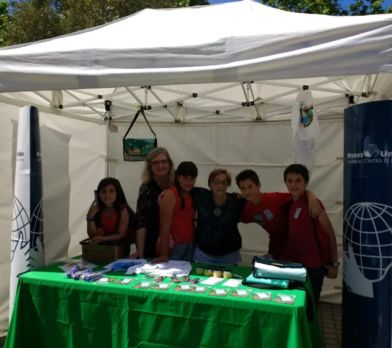 Stand de Manos Unidas con alumnos, en el mercado cooperativo