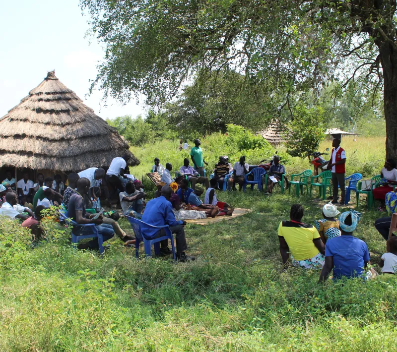 project officer in red briefing the community members during group foirmation
