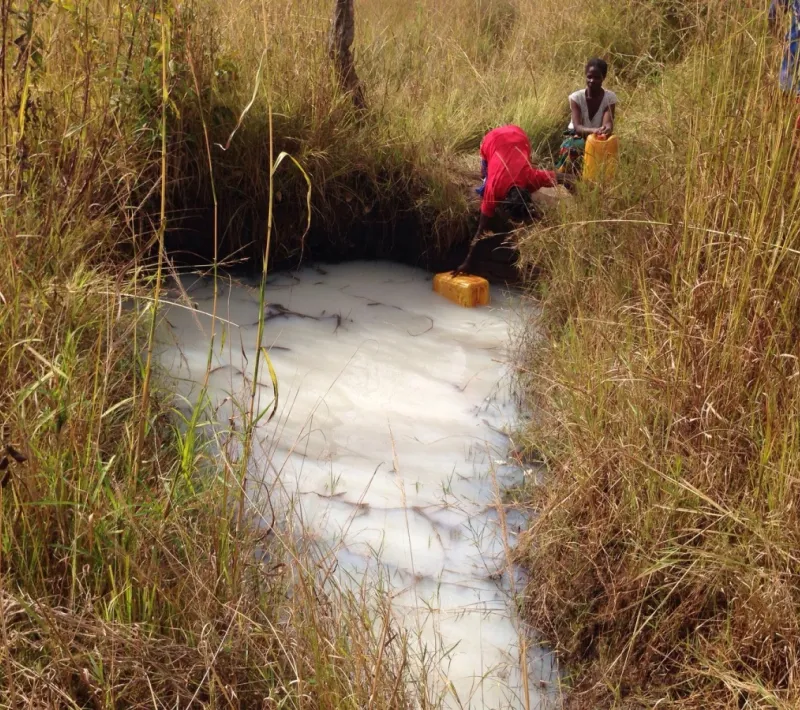Mujer sacando agua de una charca en Zambia